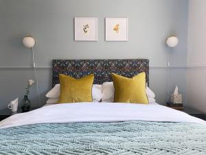 um quarto com uma cama grande e almofadas amarelas em The Emsworth B&B Hotel em Emsworth