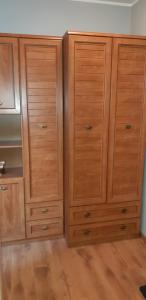 two tall wooden cabinets in a room with wooden floors at Apartament w Oliwie in Gdańsk