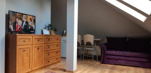 a living room with a tv on top of a dresser and a dining table at Apartament w Oliwie in Gdańsk