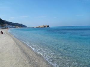 a person sitting on a beach near the water at B&B La Petite Maison in Santa Domenica