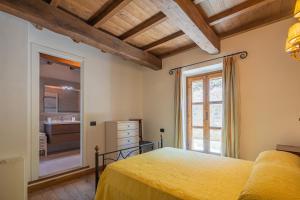a bedroom with a yellow bed and a bathroom at Convento La Perla in Carrara