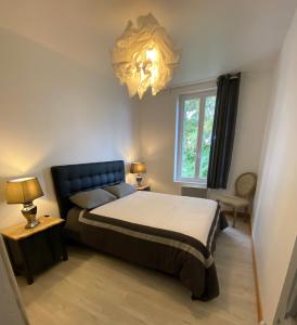a bedroom with a large bed and a chandelier at Appartement de l’abbaye in Saint-Astier