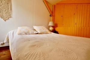 una camera con un letto bianco con due cuscini di Maisonnette au centre de Deauville a Deauville