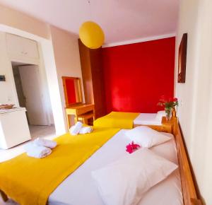 a bedroom with two beds and a red wall at Eleni's Studios in Nikiana