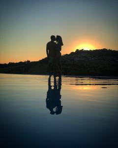 Ein Paar steht bei Sonnenuntergang im Wasser in der Unterkunft B&B Casa Fanny Riviera Del Conero in Loreto