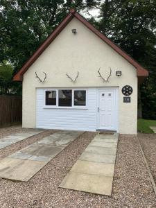 a white garage with a white door and windows at River cottage in Fort William