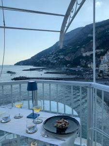 a table with a plate of food and wine glasses on a balcony at Hotel Marina Riviera in Amalfi