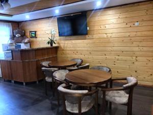 a restaurant with wooden tables and chairs and a flat screen tv at Під Магурою in Vorokhta