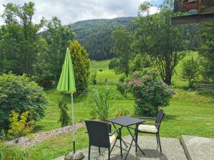 uma mesa e cadeiras com um guarda-sol verde em Almland Hütte em Pusterwald