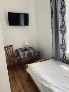 a bedroom with a bed and a table and a television at Pensjonat Makuch in Korbielów
