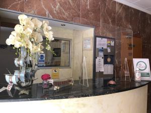 Un mostrador con un jarrón con flores blancas. en Hotel Ancla, en Oropesa del Mar