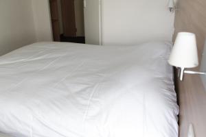 a white bed with a white comforter on top of it at Best Hotel Rouen Est / Val De Reuil in Val de Reuil