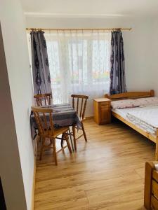 a bedroom with a bed and a table and chairs at Pensjonat Makuch in Korbielów