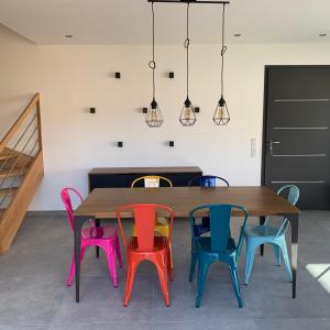 une table en bois entourée de chaises colorées. dans l'établissement La Bellangerie Gîte et Spa, à Forcé