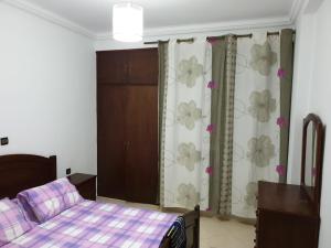 Résidence EL AMAL في مرتيل: غرفة نوم بسرير وستائر عليها ورد