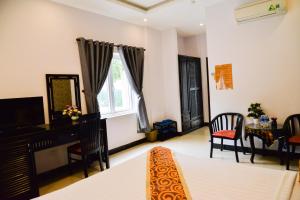 a bedroom with a bed and a desk and a window at Nohana Hotel in Mui Ne