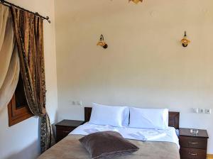1 dormitorio con 1 cama con sábanas blancas y ventana en Guesthouse Syntrofia, en Psarádes