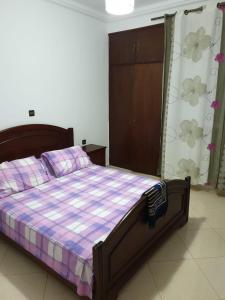 um quarto com uma cama com uma colcha roxa e branca em Résidence EL AMAL em Martil