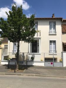 a white house with a tree in front of it at Maison Bernadette - Premier Etage in Vitry-sur-Seine