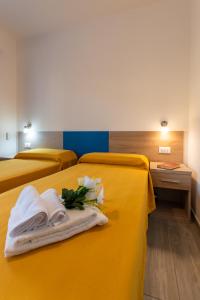 une chambre d'hôtel avec 3 lits et des serviettes. dans l'établissement Bed & Blu, à La Caletta