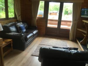 un soggiorno con divani in pelle nera e una veranda di Chalet 2 a Tyndrum