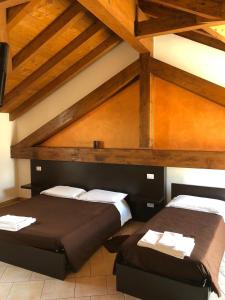 2 camas en una habitación con techos de madera en La Siesta Bed&Residence, en Cardano al Campo