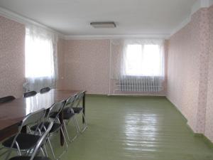 an empty room with chairs and a table and two windows at Rubeni in Pilskalne