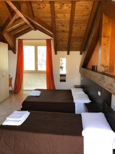 two beds in a room with wooden ceilings at La Siesta Bed&Residence in Cardano al Campo