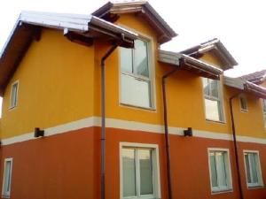 Casa de color amarillo y naranja con ventanas en La Siesta Bed&Residence, en Cardano al Campo