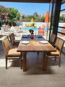 einen Holztisch mit Stühlen und einen Tisch mit Weingläsern in der Unterkunft Arhodiko Hotel in Ammoudara