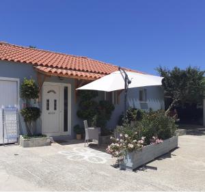 a blue house with an umbrella and some flowers at Vasiliki Residence in Pylos