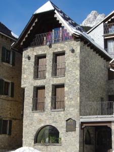 Edificio de piedra con ventanas y balcón en Hotel Valle De Izas, en Sallent de Gállego