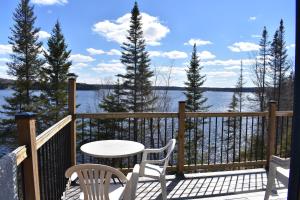 a table and chairs on a deck with a view of the water at Le Gite de la Renarde in Saint-Félix-d'Otis