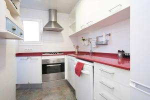 uma cozinha com armários brancos e bancadas vermelhas em Apartamento Parc Güell em Barcelona