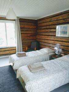 a bedroom with three beds and a chair and a window at Hannaksen tila in Korppoo