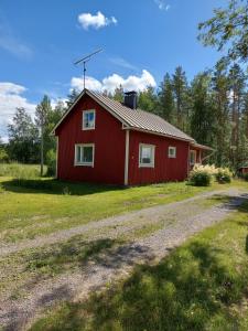 a red barn with a gravel road in front of it at Esterin Tupa, Alajärvi 