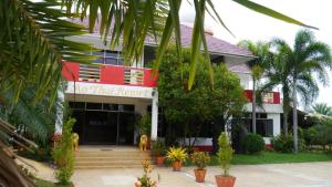 un bâtiment rouge et blanc avec un chien devant lui dans l'établissement Ao Thai Resort, à Sathing Phra