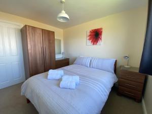 a bedroom with a white bed with two towels on it at Copthorne - Tintagel in Tintagel