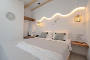 a white bedroom with a large white bed with pillows at Birikos Studios & Apartments in Agios Prokopios