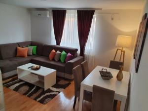 een woonkamer met een bank en een tafel bij Family Apartments in Zaječar