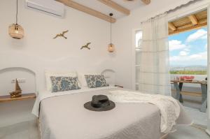 a white bedroom with a bed with a hat on it at Birikos Studios & Apartments in Agios Prokopios