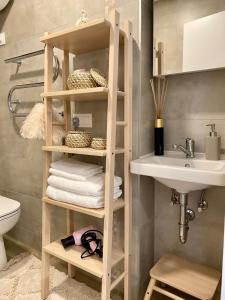 a bathroom with a wooden shelf with towels and a sink at Modern Studio Juodkrante in Juodkrantė