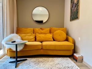 a living room with a yellow couch and a mirror at Modern Studio Juodkrante in Juodkrantė