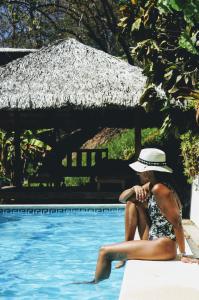 una mujer sentada en el borde de una piscina en Funky Monkey Lodge en Santa Teresa Beach