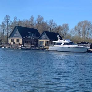 een boot geparkeerd voor een huis op het water bij Ausflugsrestaurant & Pension Aalbude & Hausfloßvermietung am Kummerower See in Dargun