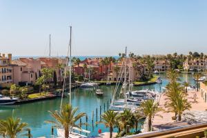 eine Gruppe von Booten, die in einem Hafen mit Palmen angedockt sind in der Unterkunft Sotogrande Ribera del Marlin apartment in Sotogrande