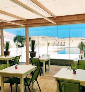 un restaurante con mesas y sillas y vistas a la piscina en La Trottoria Agriturismo, en Otranto