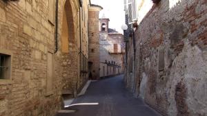 an alley between two brick buildings with a clock tower at Benvenuti Altrove in Cella Monte