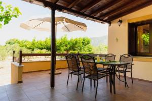 a patio with a table and chairs and an umbrella at Karavos Grove in Káto Lekhónia