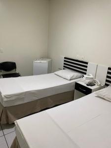 a hotel room with two beds and a television at Neves Hotel in Goiânia